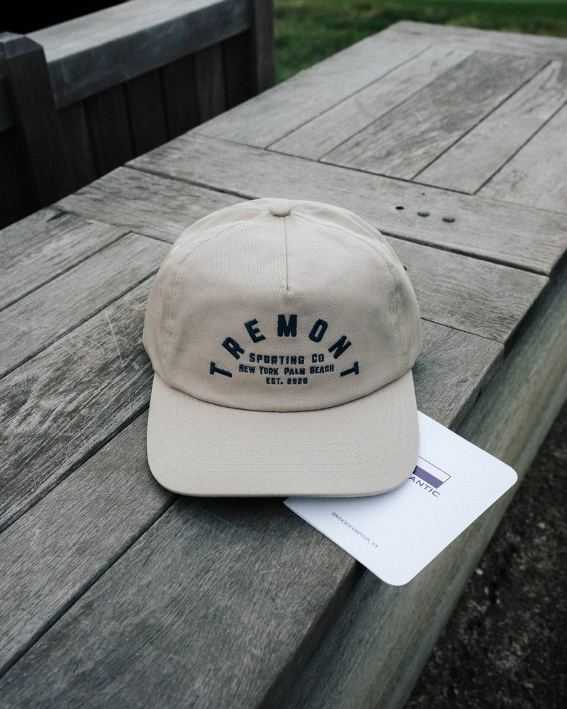 Beige cap with 'Tremont' branding on a wooden surface