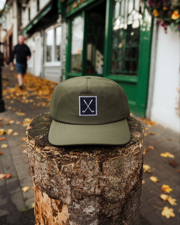 Green cap with a logo on a wooden post in an urban setting