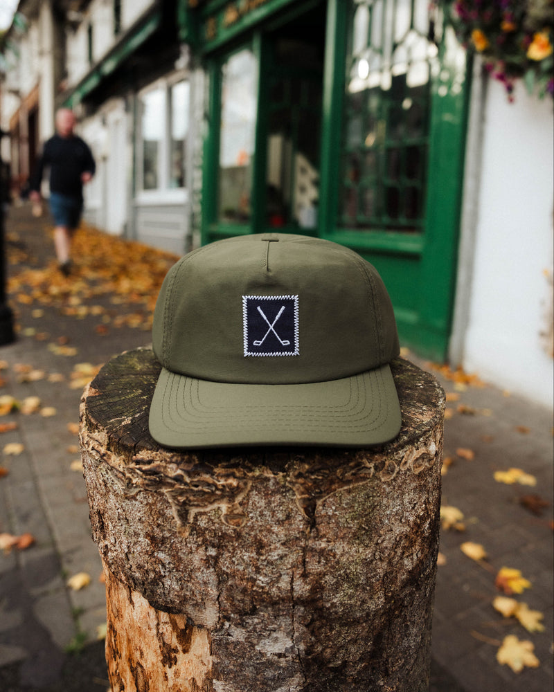 Green cap with a logo on a wooden post in an urban setting