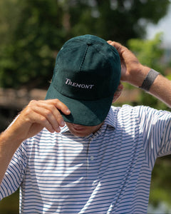 Person wearing a green cap with 'Tremont' branding outdoors.