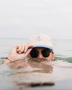 Person wearing a cap and sunglasses partially submerged in water